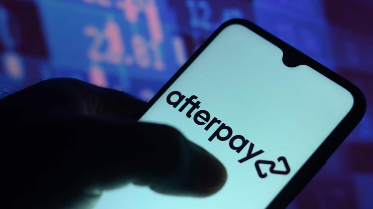 A person holding a phone with a screen open that reads: "Afterpay".