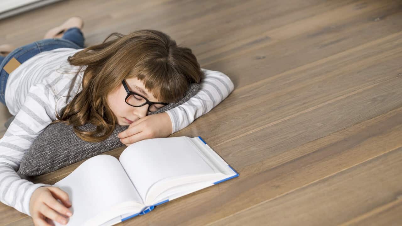 High angle view of teenage girl sleeping while studying on floor
