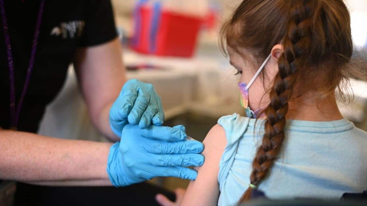A nurse administers a vaccine to a young girl.