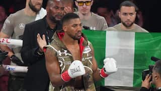 A boxer stands inside a ring with his team behind him