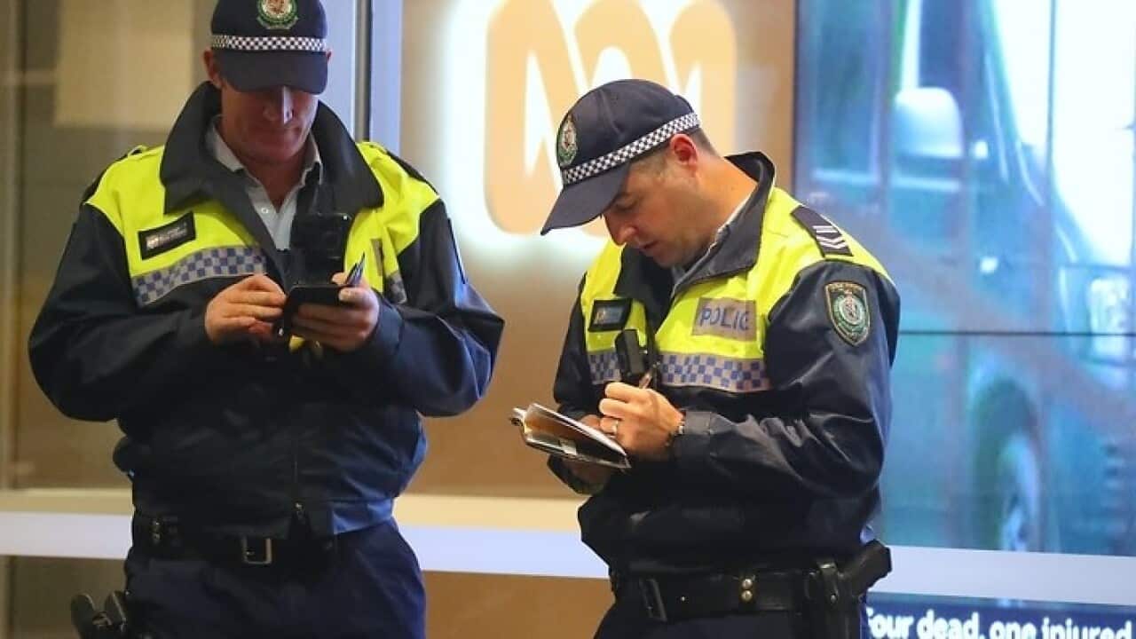ABC raidTwo policemen stand in front of an ABC logo at the main entrance to the ABC building located at Ultimo in Sydney