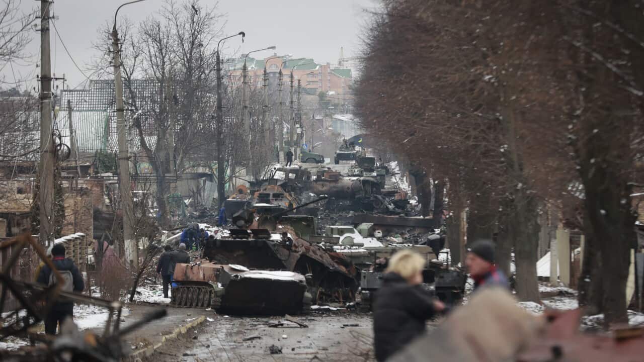 People look at the gutted remains of Russian military vehicles on a road in the town of Bucha, close to the capital Kyiv, Ukraine (AAP)