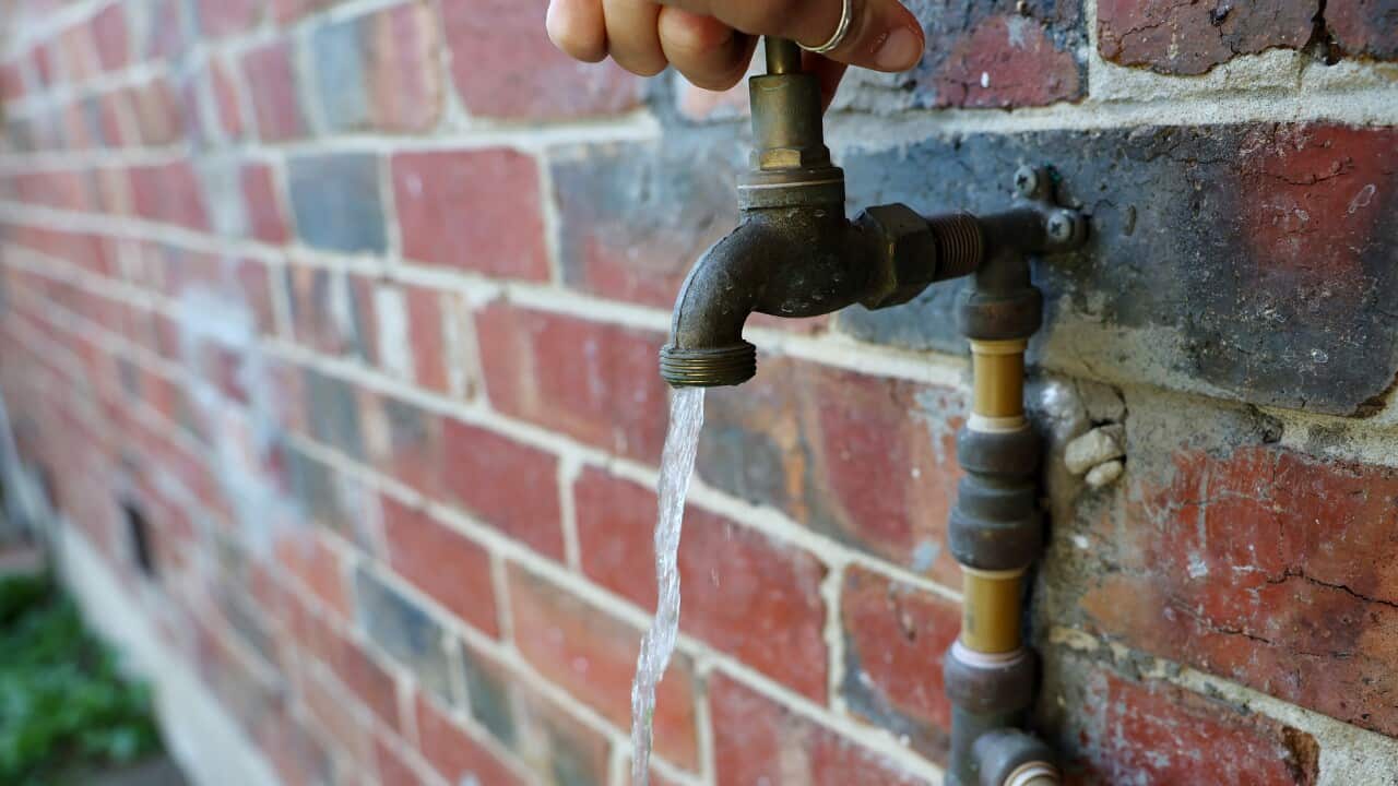 A hand turning on a tap