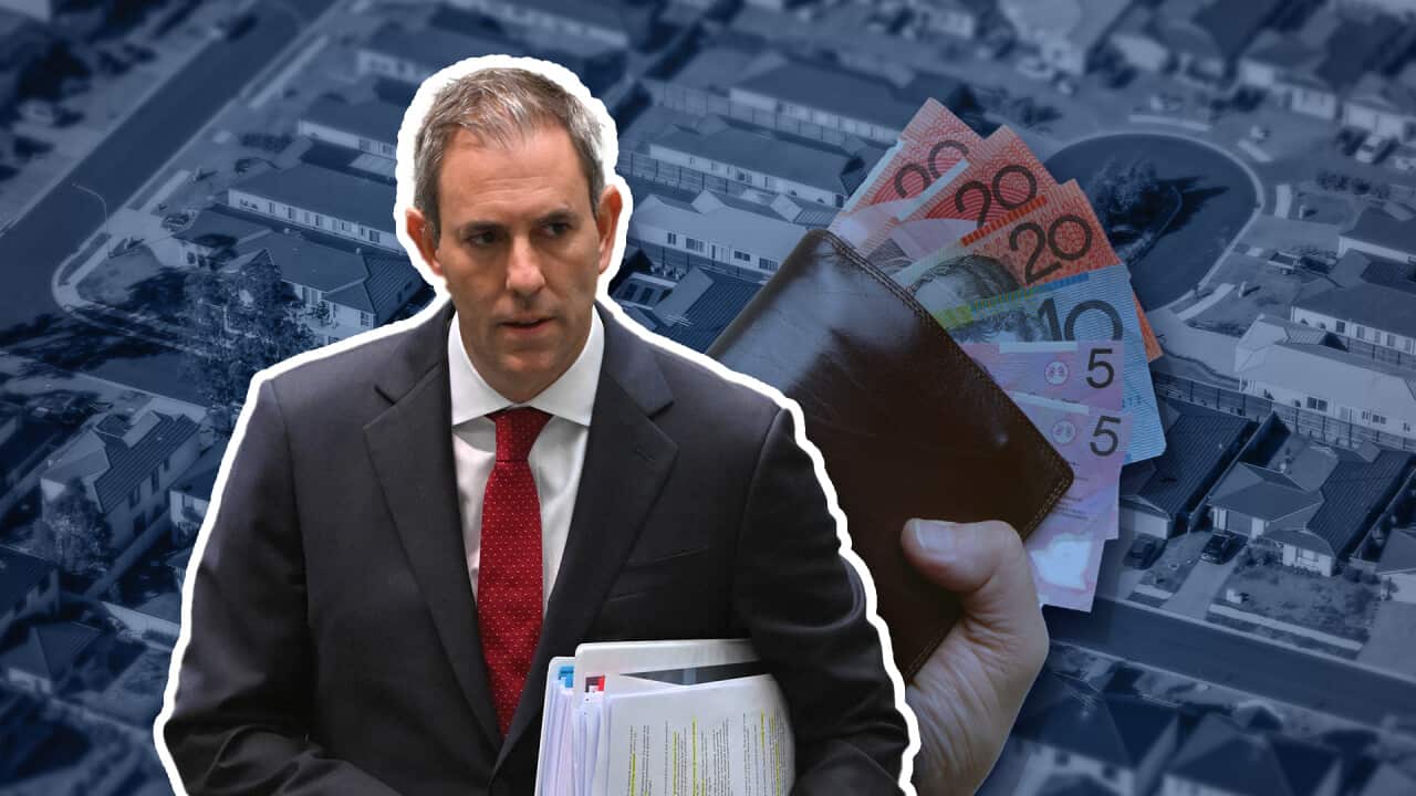 A man in a suit, holding paperwork under his arm.