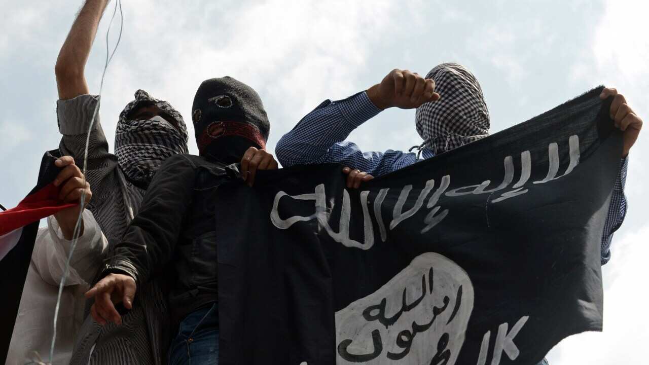 Demonstrators hold up an Islamic State flag