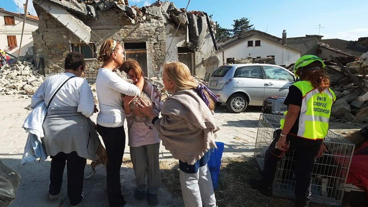 Women cry in front of damaged houses in a street in the central Italian village of Illica, near Accumoli, on August 24, 2016 