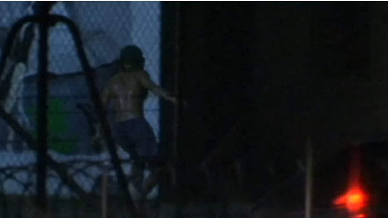 A teenager at Don Dale is seen through the fence.