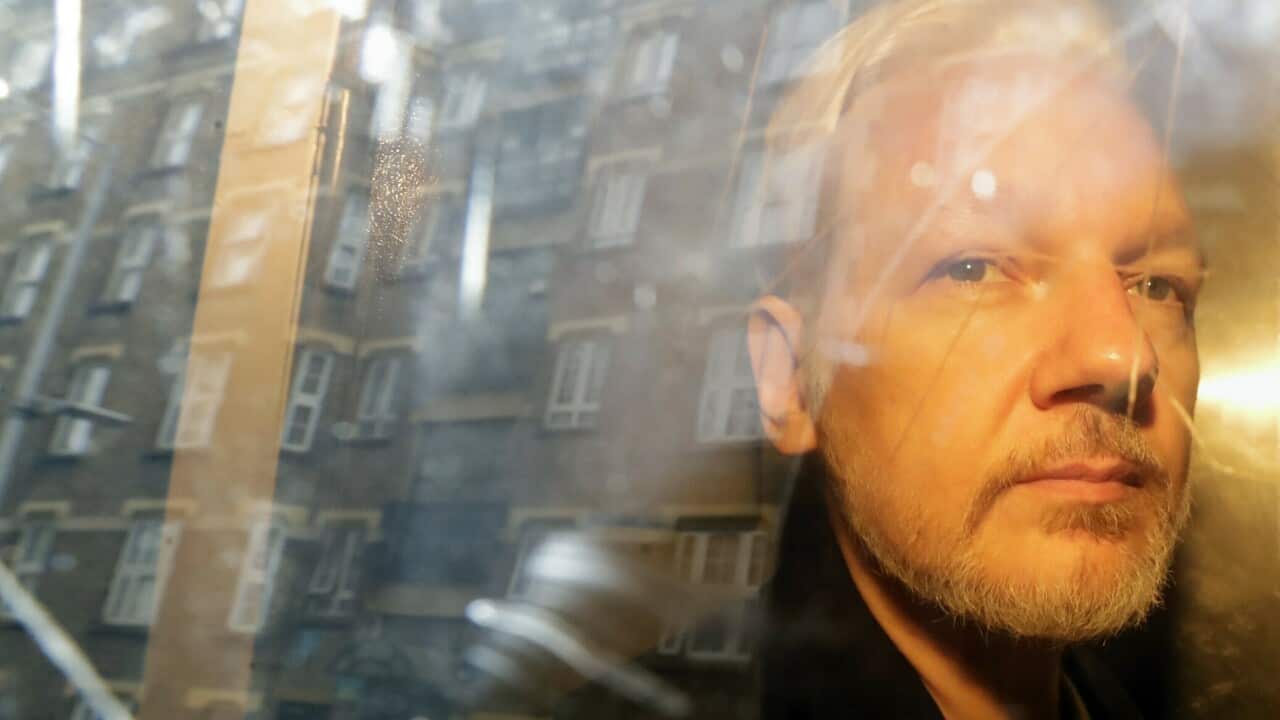 Buildings are reflected in the window as WikiLeaks founder Julian Assange is taken from court