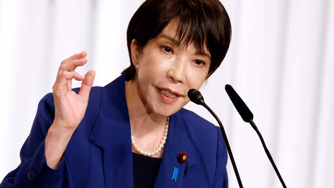 A woman with black hair wearing a blue suit.
