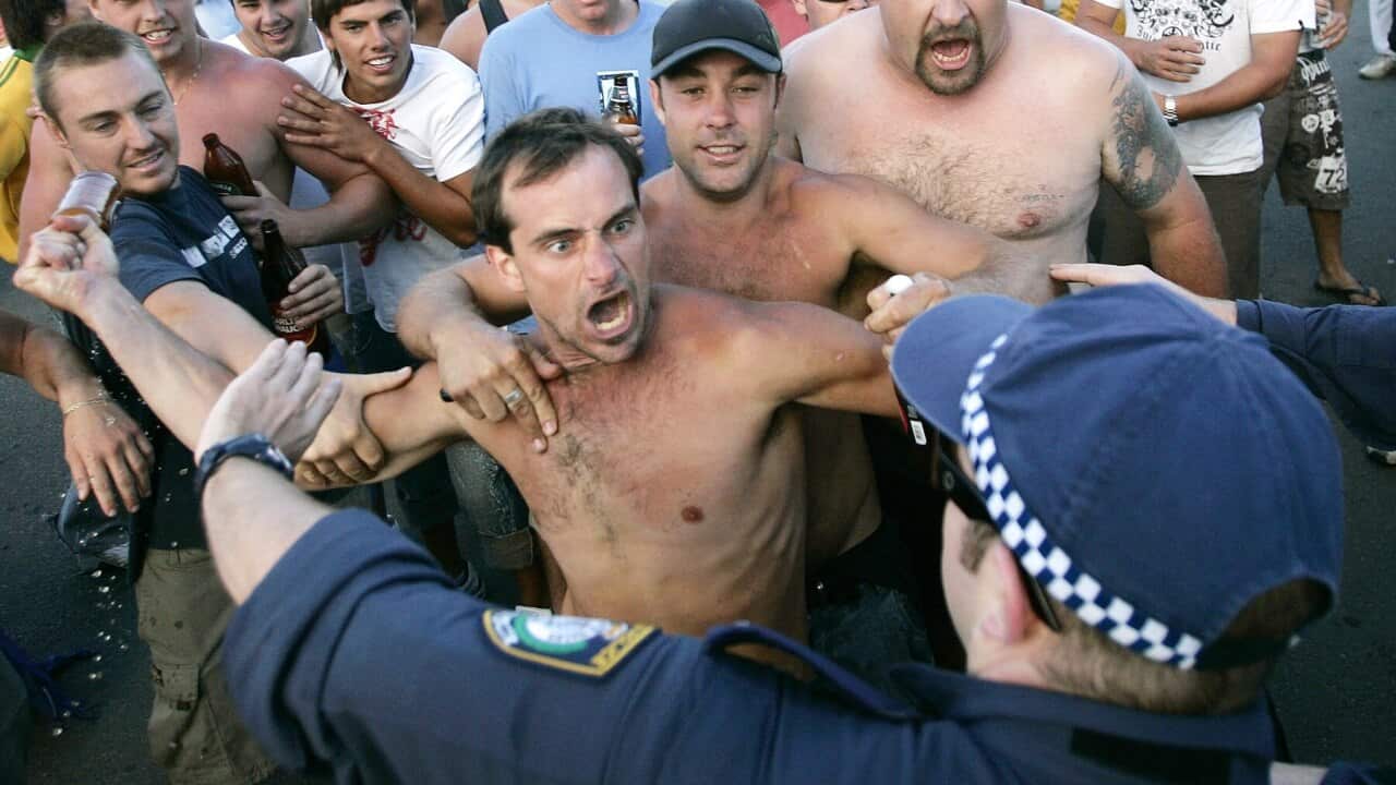 A man tries to hit police with a beer bottle during the Cronulla Beach riot in 2005