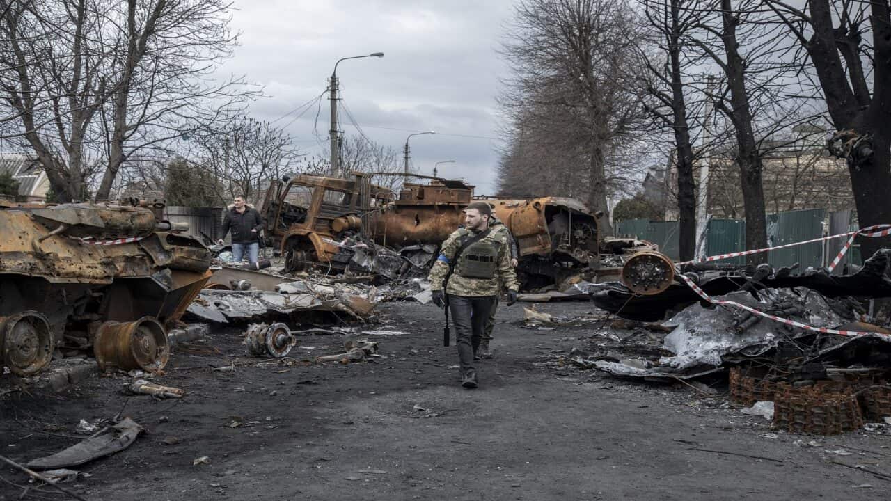 Ukrainian servicemen walk amid the destruction on a street in the town of Bucha