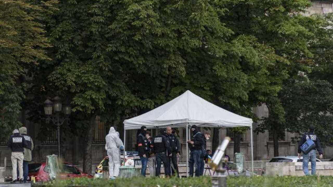 French police officials and investigators gather at the site of an attack near the entrance of Notre-Dame cathedral in Paris