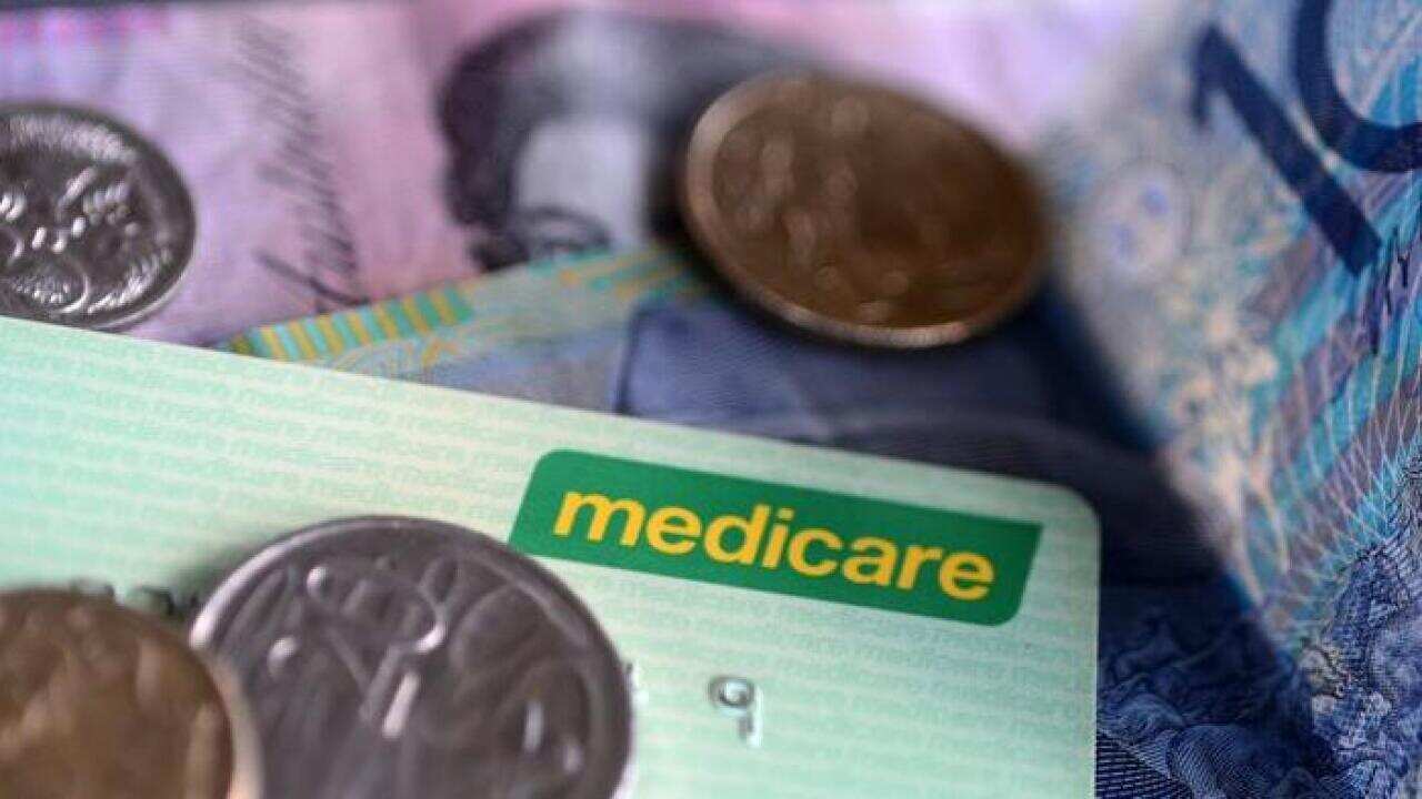 Bank notes and coins are seen with a Medicare Card in Brisbane, Wednesday, May 1, 2013. Prime Minister Julia Gillard today announced a levy to fund the National Disability Insurance Scheme. (AAP Image/Dave Hunt) NO ARCHIVING
