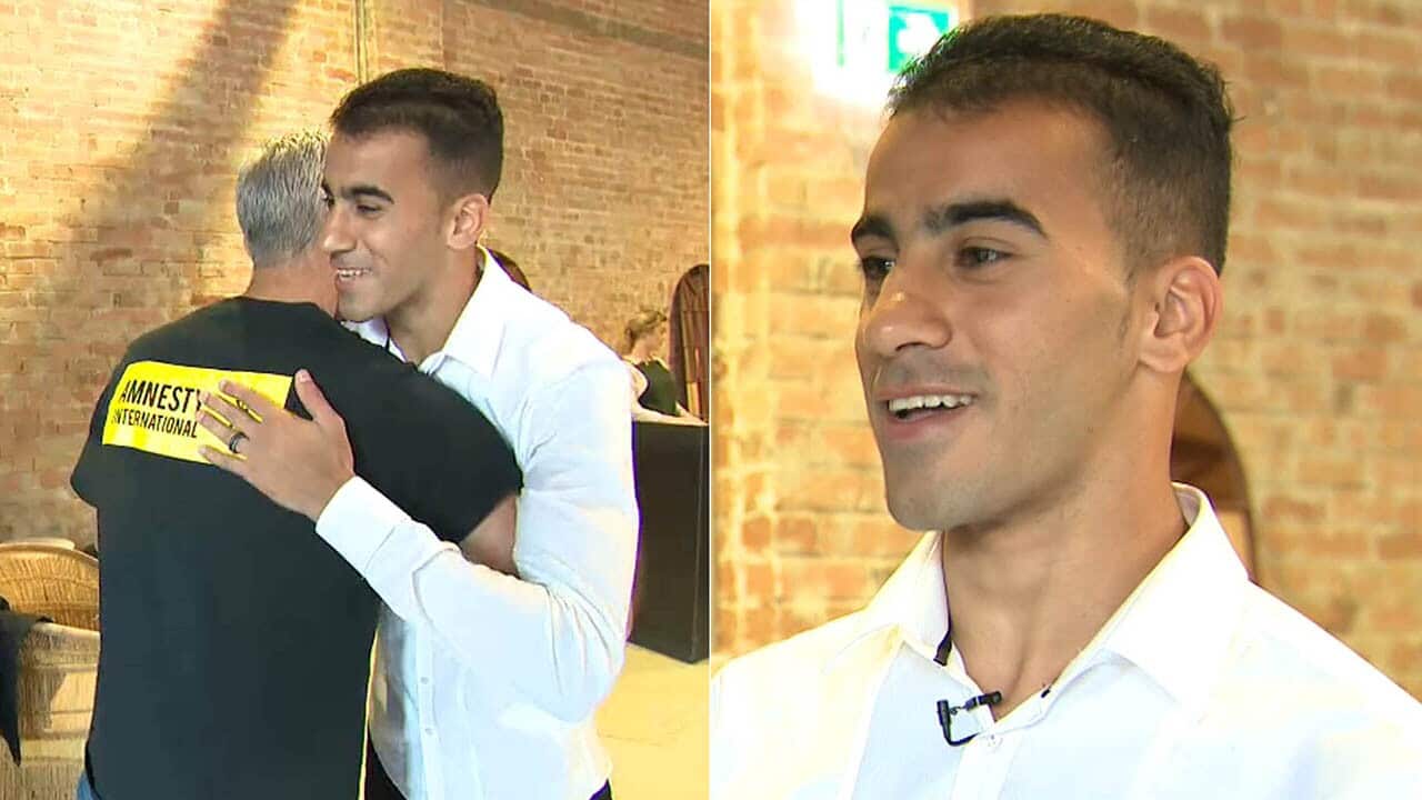 The refugee footballer hugs former Soceroo Craig Foster after his release.