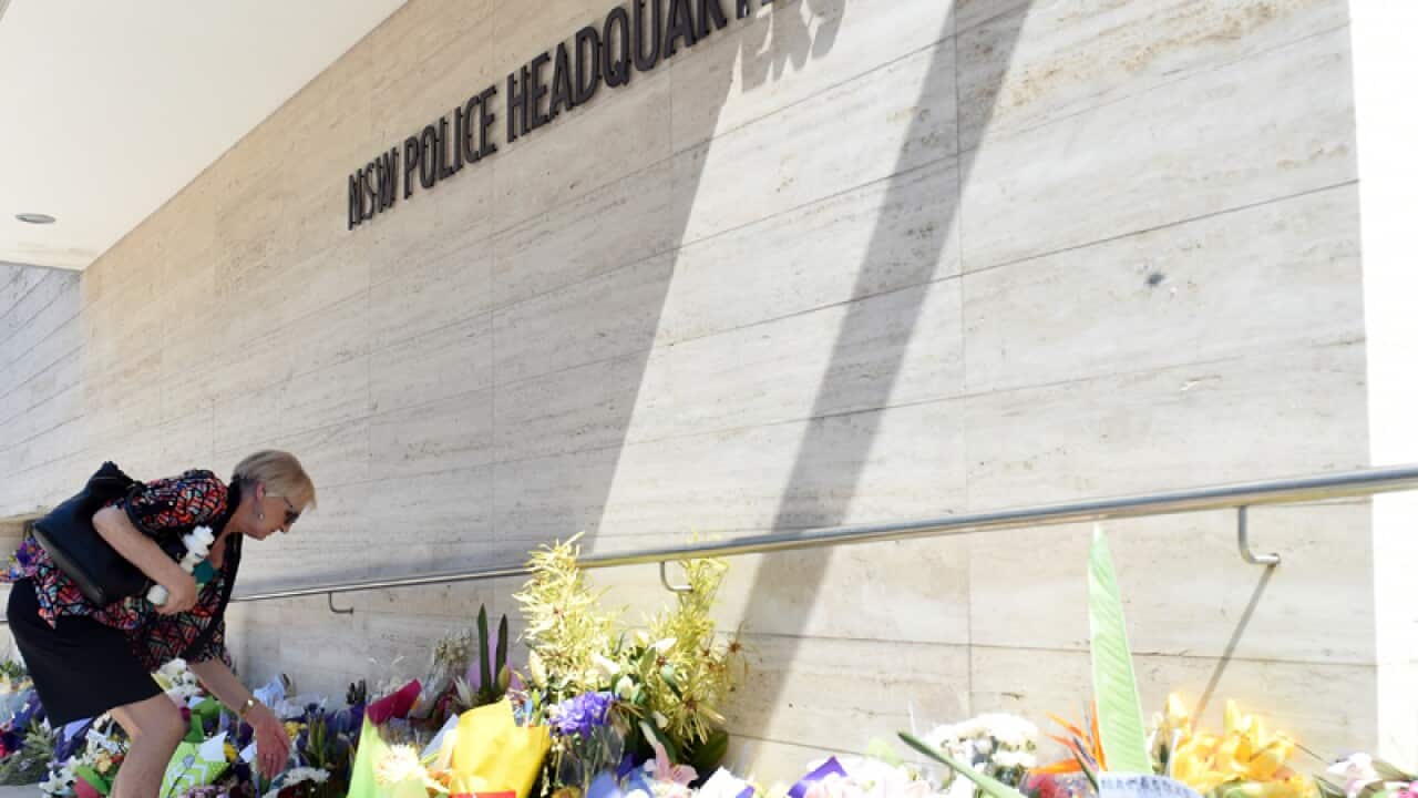 A woman looks at flower placed for police accountant Curtis Cheng
