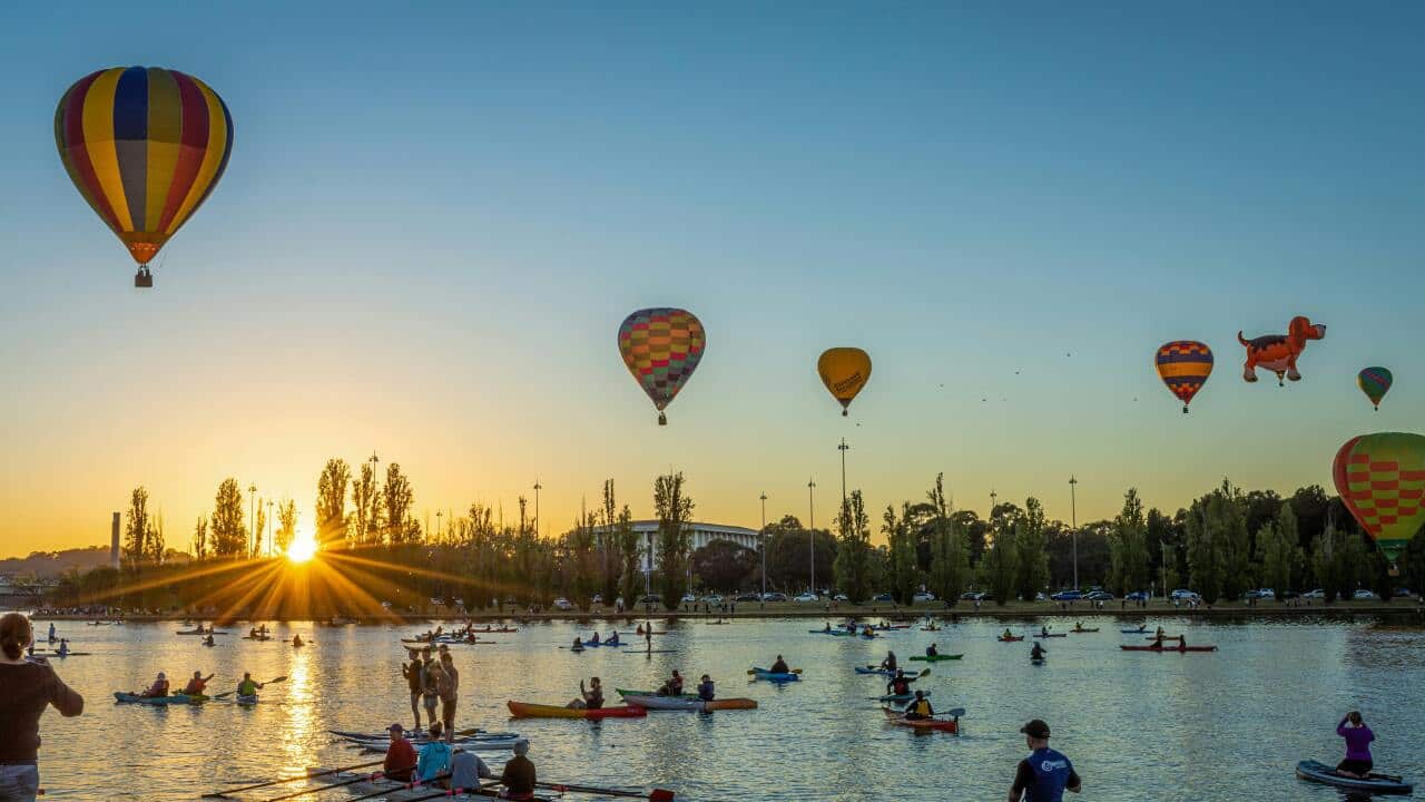 A view of hot air balloons and kayaks during sunrise in Canberra, Australia.