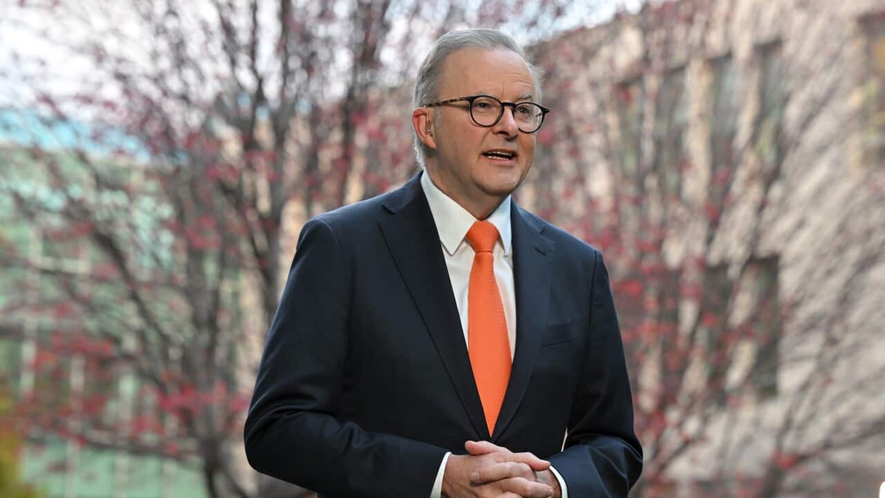 Anthony Albanese vestido con un traje oscuro y corbata naranja y hablando afuera