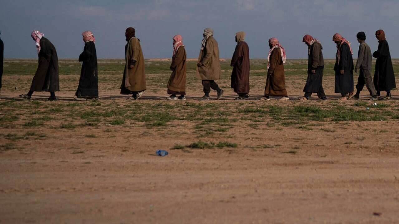 Men walk to a screening point in eastern Syria