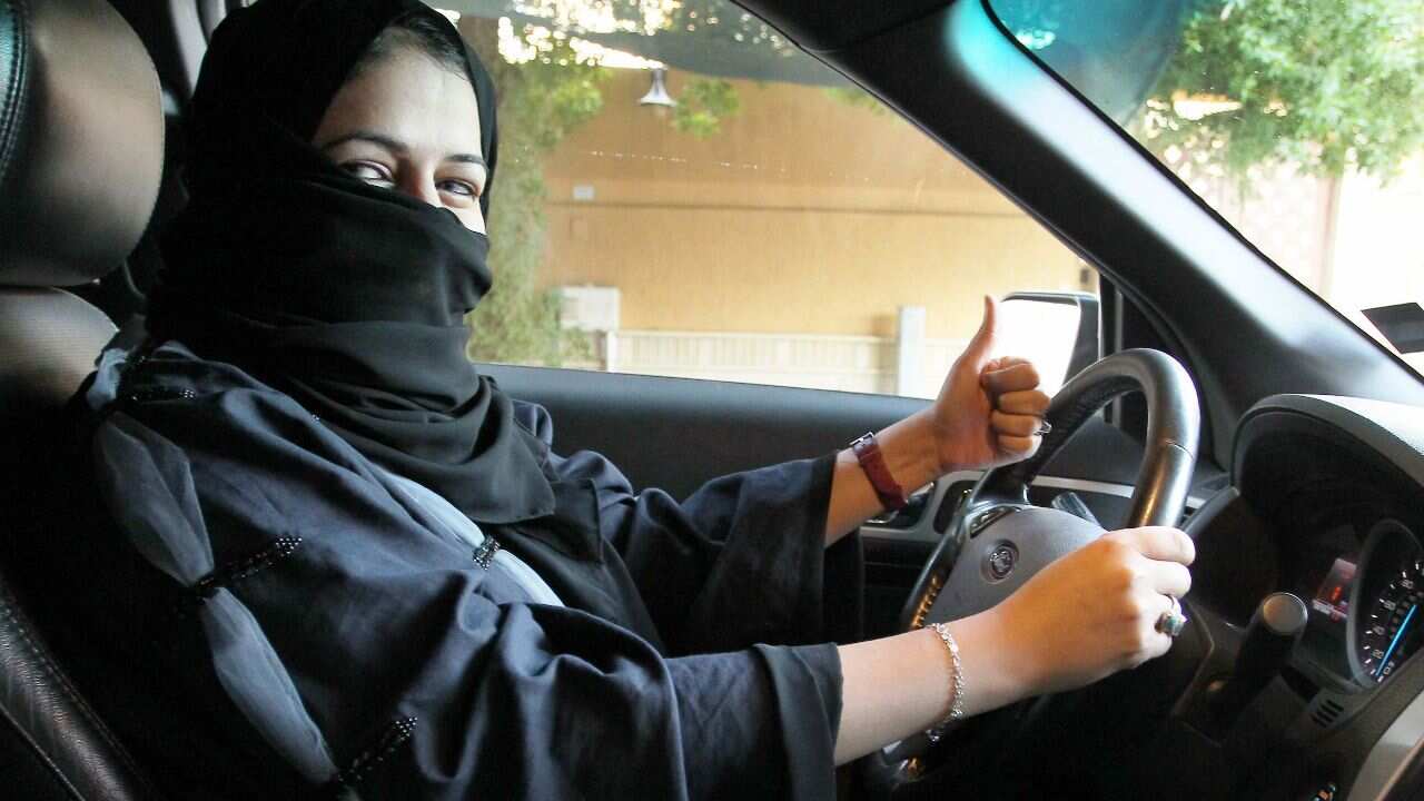 A woman gives a thumb up as she sits behind the wheel of a car in Riyadh, Saudi Arabia.