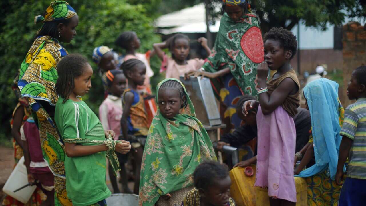 Muslim children gather at a water pump outside a mosque