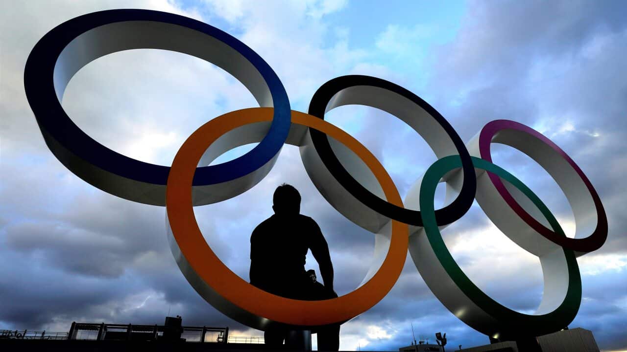 A man poses for a photo in a set of Olympic rings outside the Olympic Stadium in Tokyo.