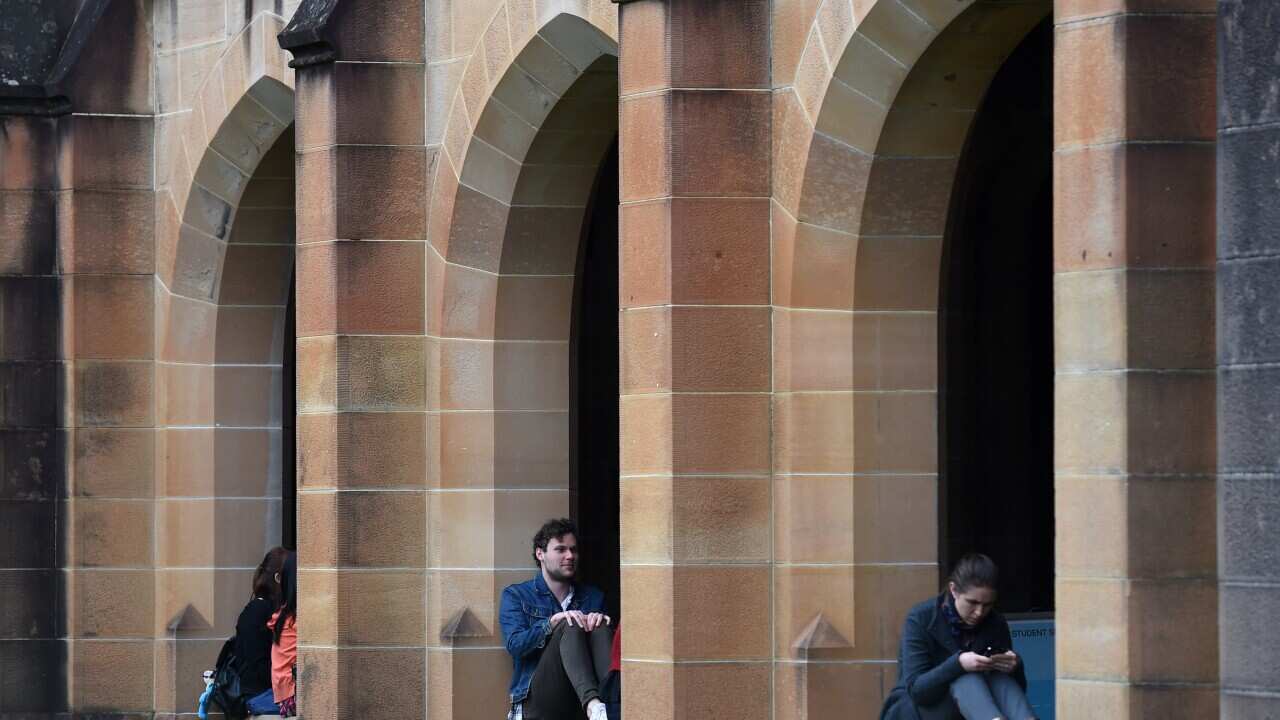 Students sit next to the quadrangle at the University of Sydney