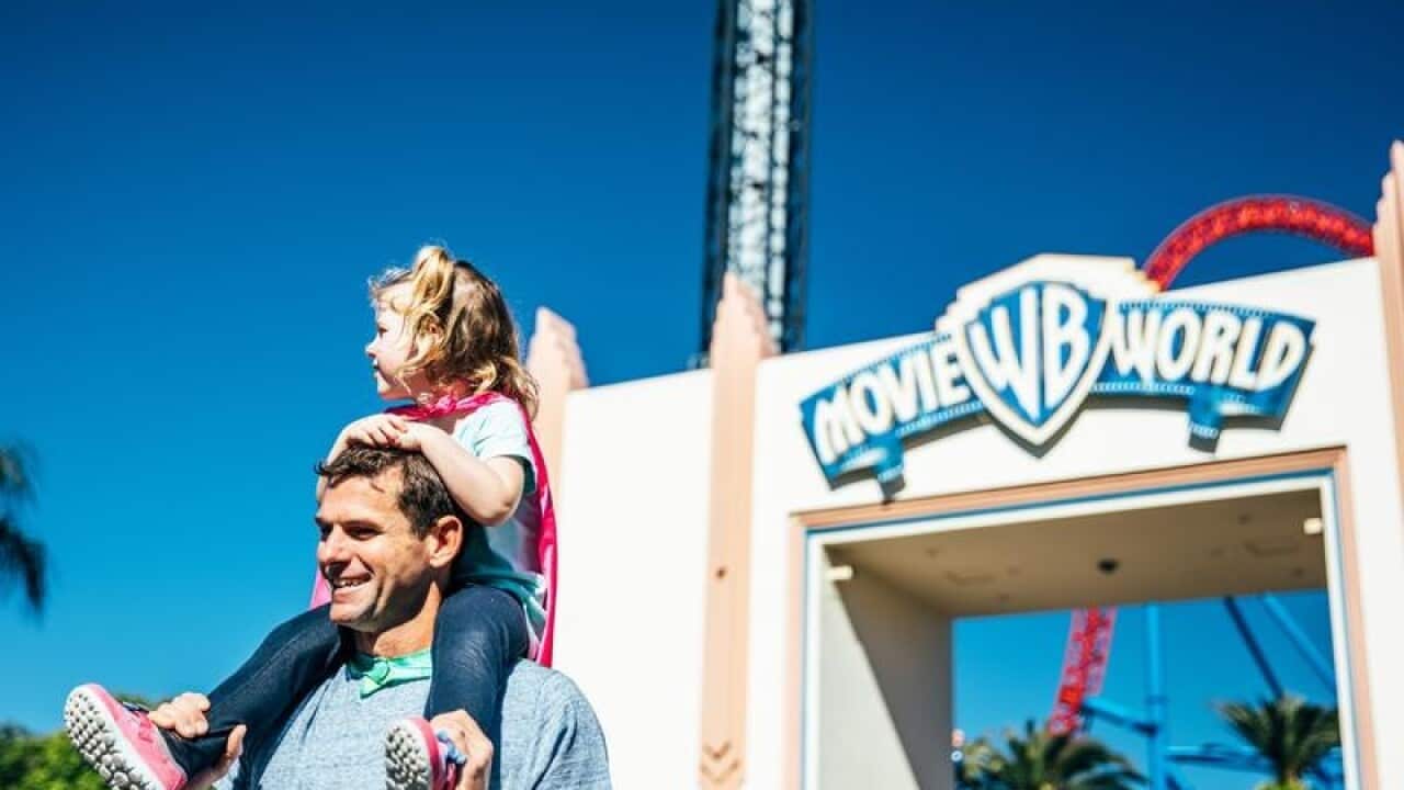 A father with his daughter on his shoulders outside Movie World.