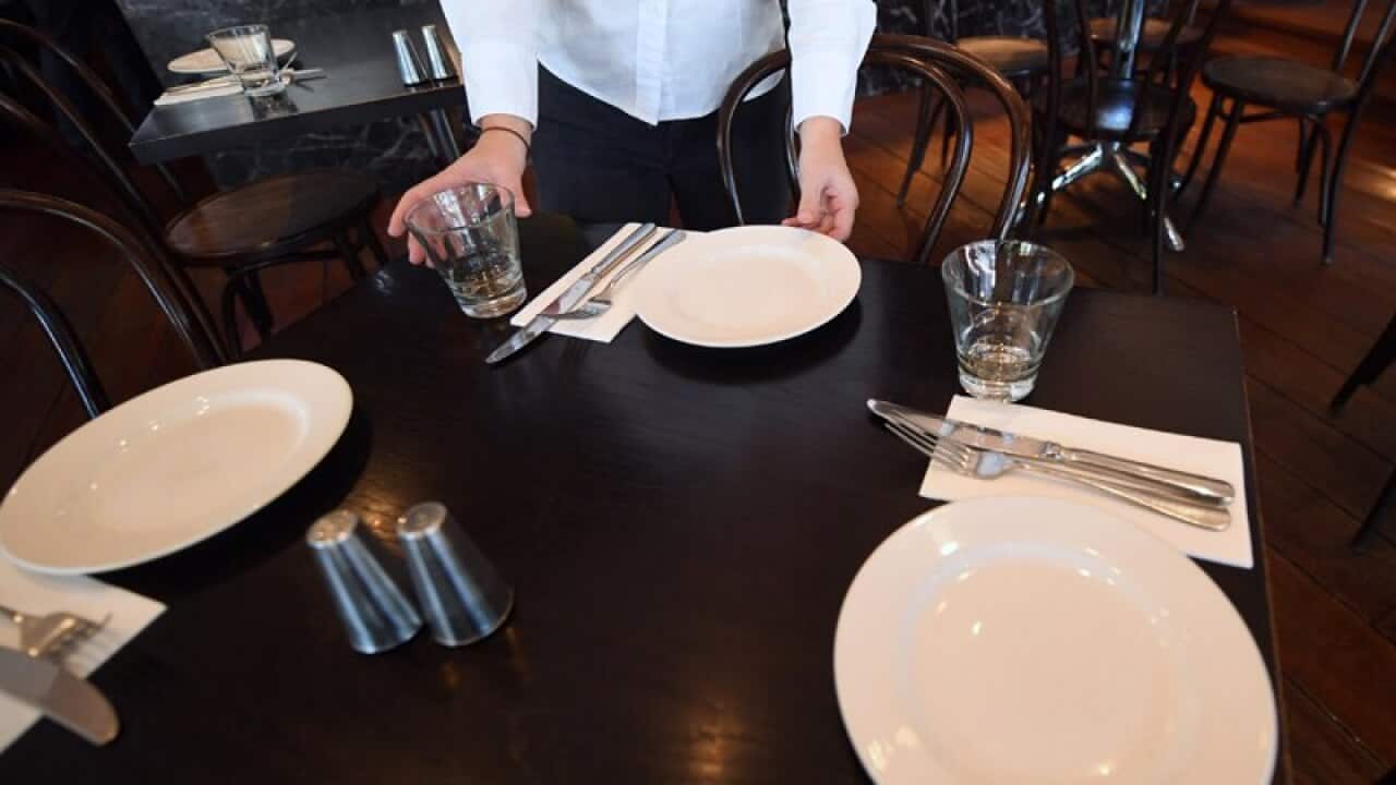 A waitress sets up a table at a restaurant in Canberra