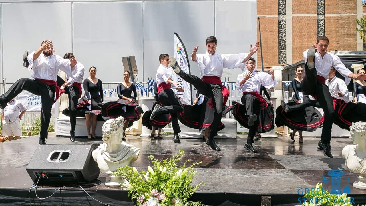 Traditional Greek dancing performance where the males are spaced apart and kick their feet into the air.