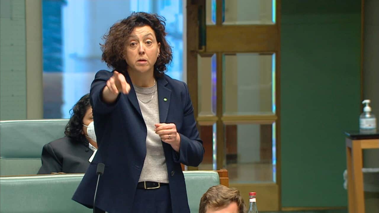 A woman in a suit points her finger at someone in the distance. 