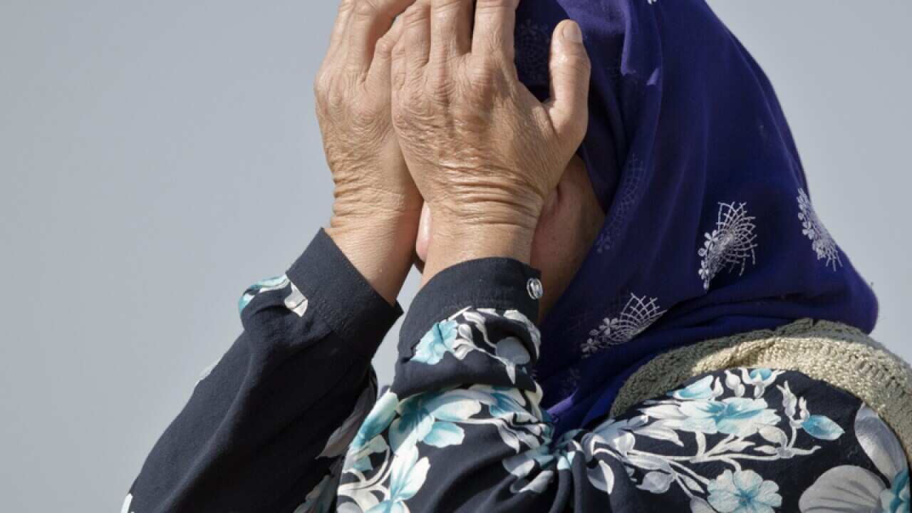 A woman covers her eyes after watching fighting in Kobani