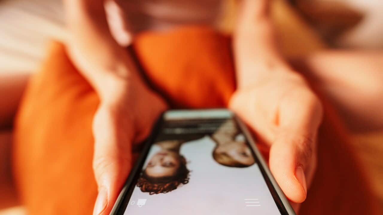 Hand holding smartphone shopping online at home in casual setting