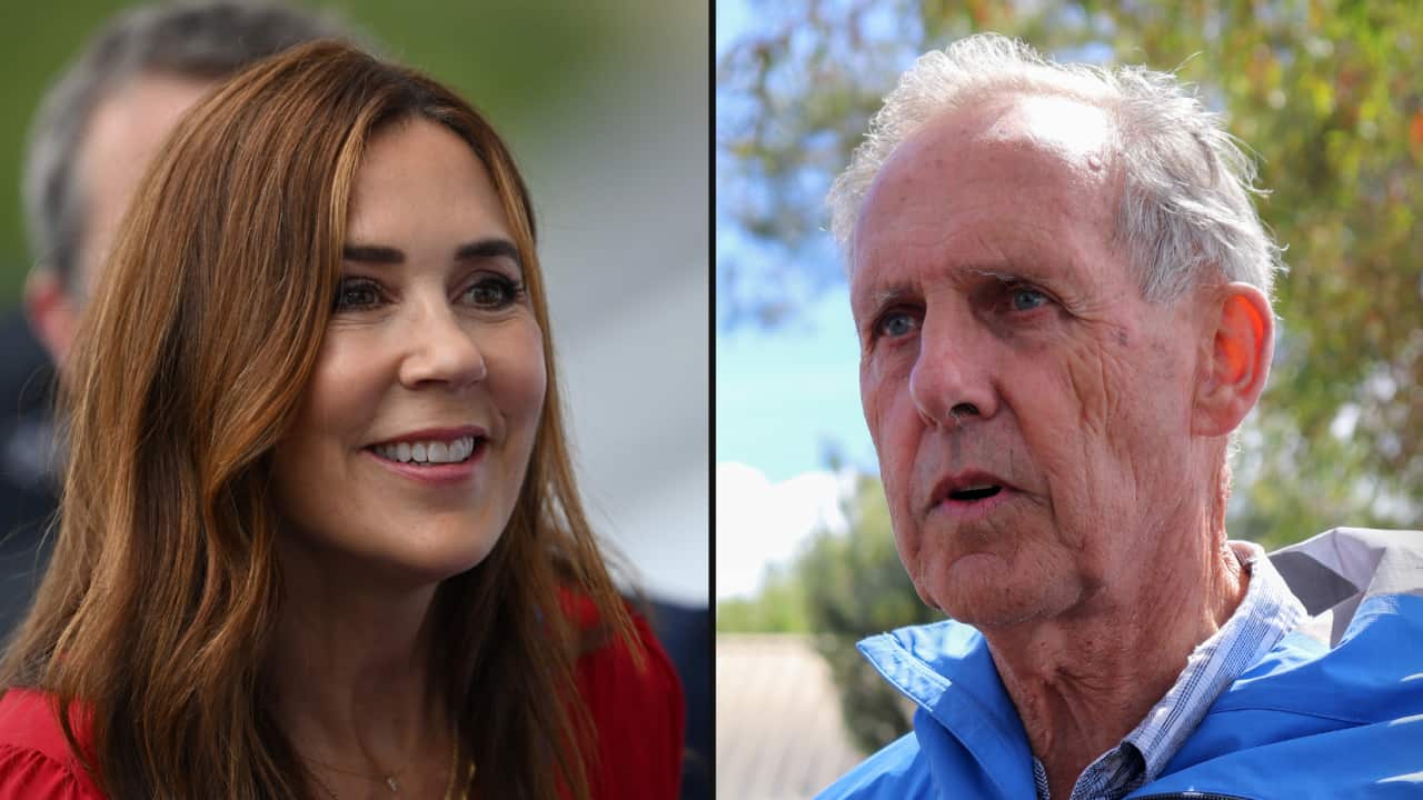 A brunette female on the left in a red top. On the right is a grey-haired man in a blue rain jacket.