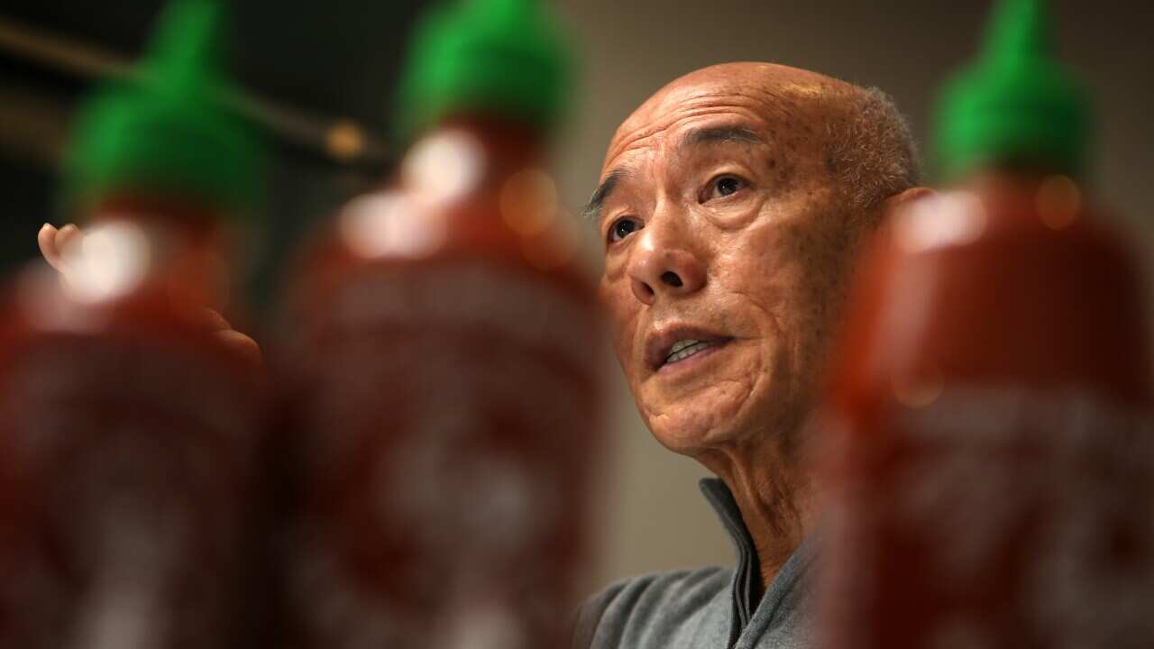 A man next to hot sauce bottles.