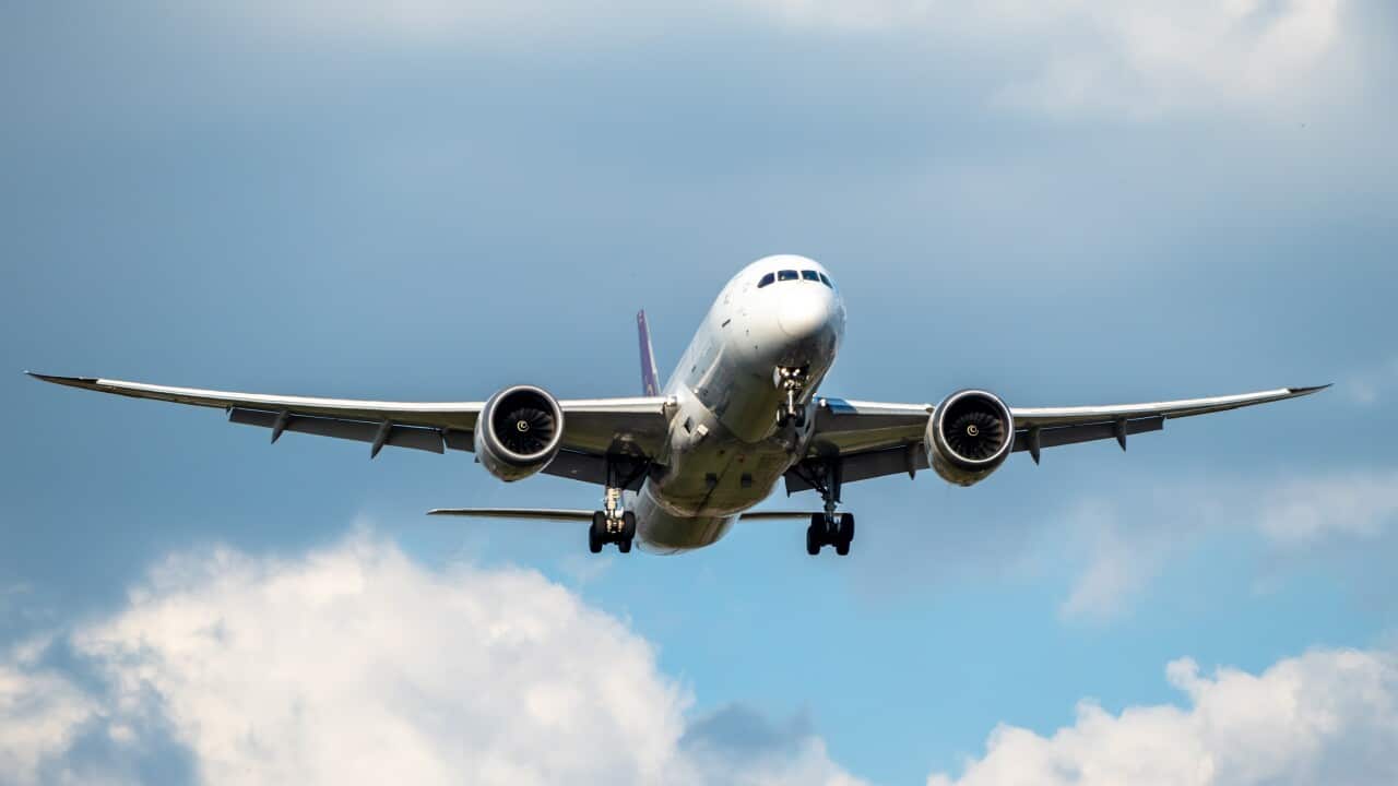 Front view of white 777 commercial flight airplane taking off or landing from the Airport runway with no visible markings or livery. Blue sky sunny back drop with some clouds