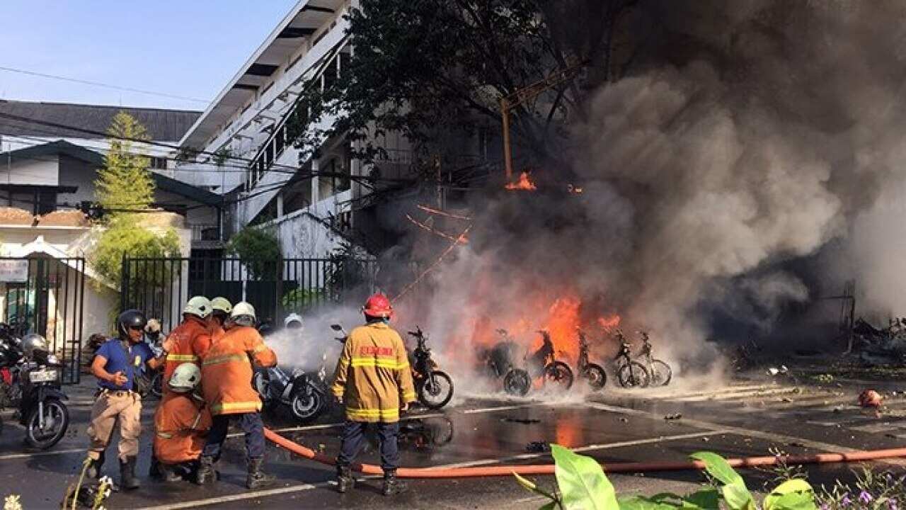 Firemen extinguishing vehicles on fire shortly after a bomb blast at a church in Surabaya – 13 May 2018.