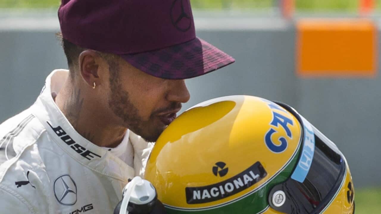 Driver Lewis Hamilton kisses an Ayrton Senna helmet