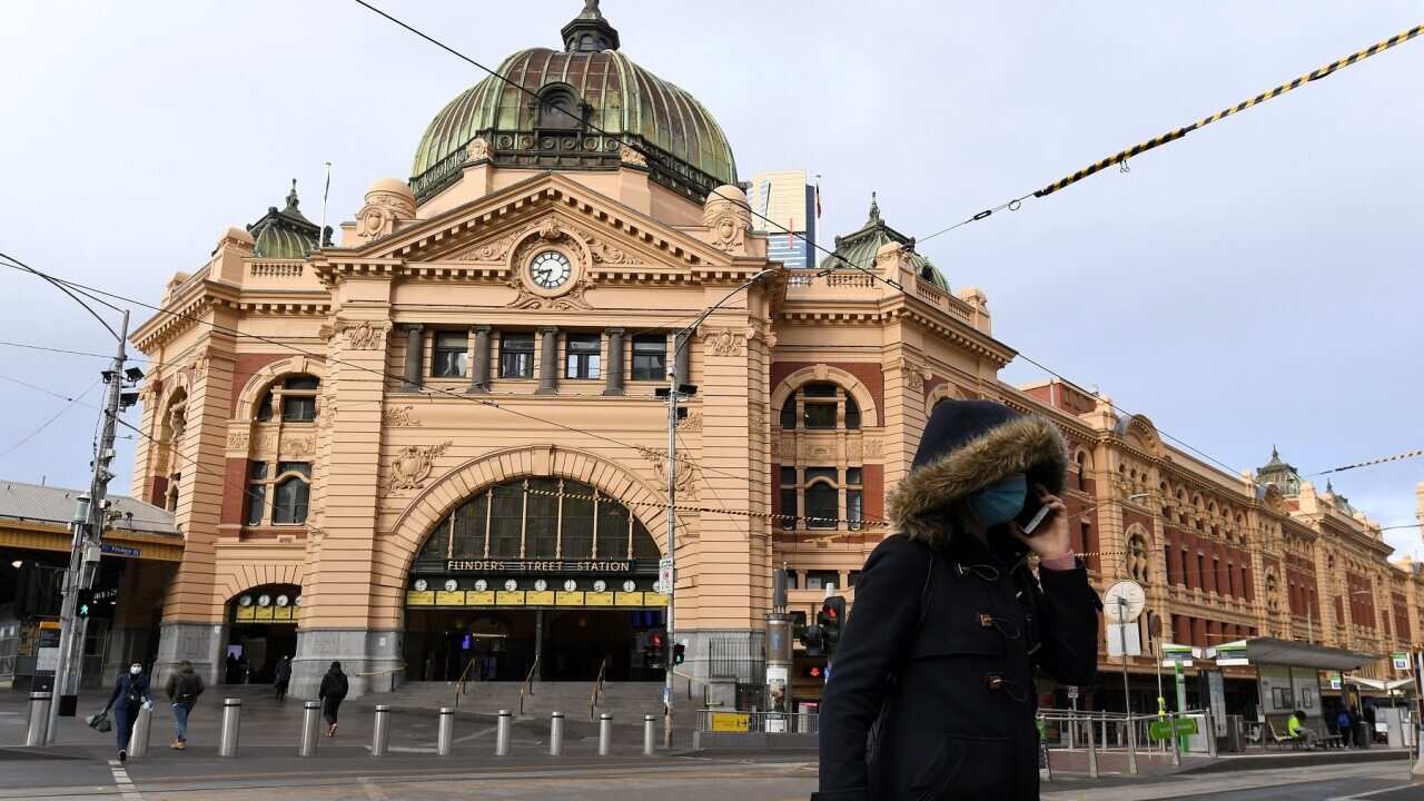 A person wearing a face mask is seen outside of Flinders Street Station in Melbourne.