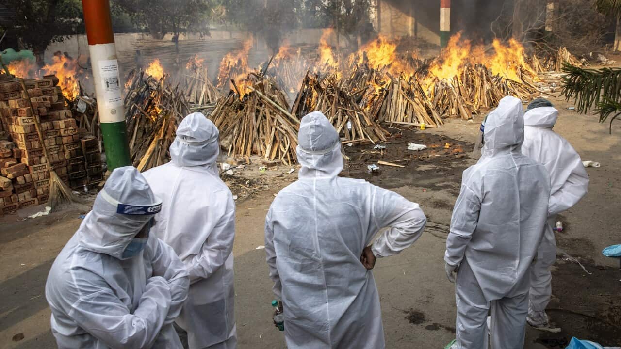 Visitors in PPE suits at a cremation site in New Delhi