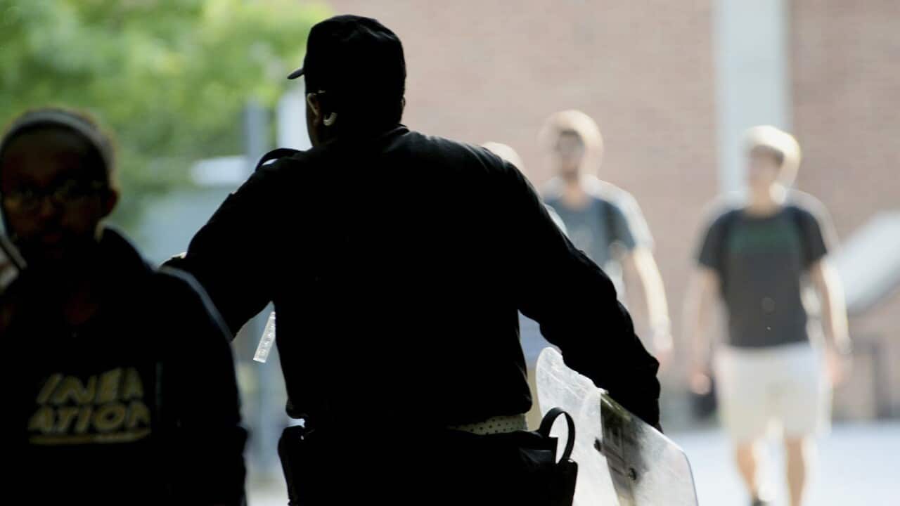 A UNC Charlotte campus police officer carries a tactical shield onto campus.