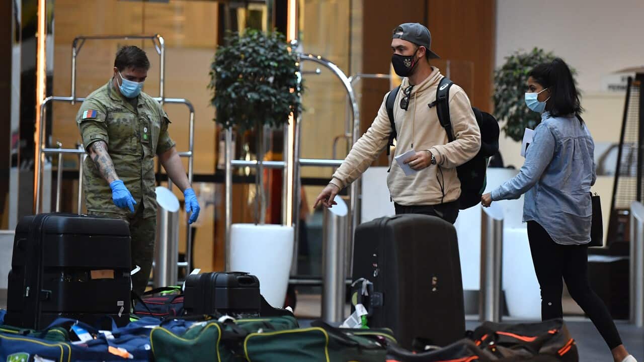 A civilian wearning a cream-coloured sweatshirt and ADF member in army fatigues stand in front of piles of luggage, pointing at various items.