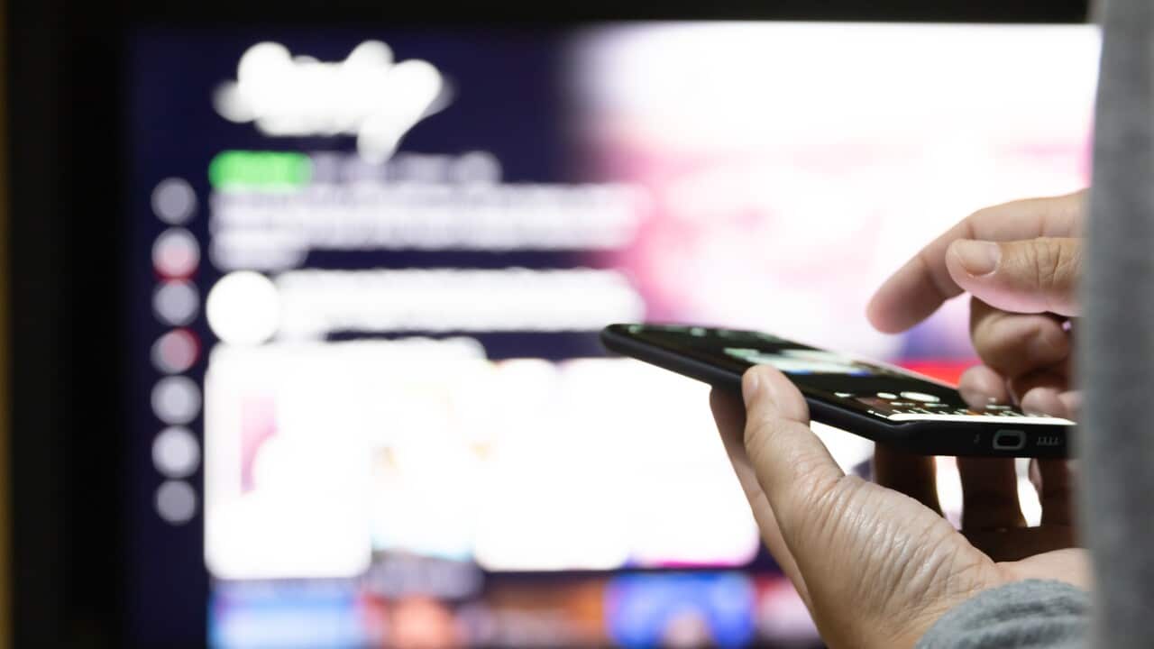 Close up asian man control televistion with mobile device.