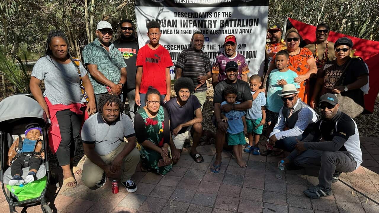 Members of Perth’s Papua New Guinea community in front of an Anzac Day banner paying tribute to soldiers who served alongside Australian troops. (SBS).jpg