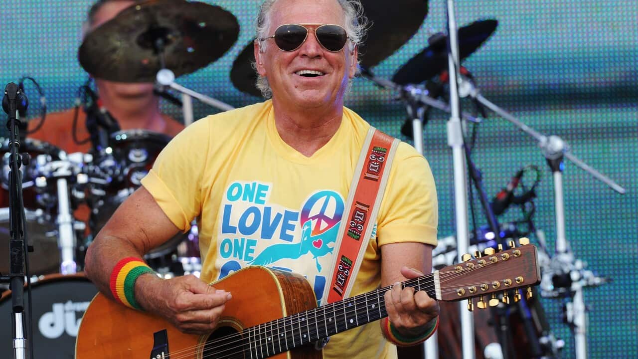 A man in a yellow shirt performing with an acoustic guitar.