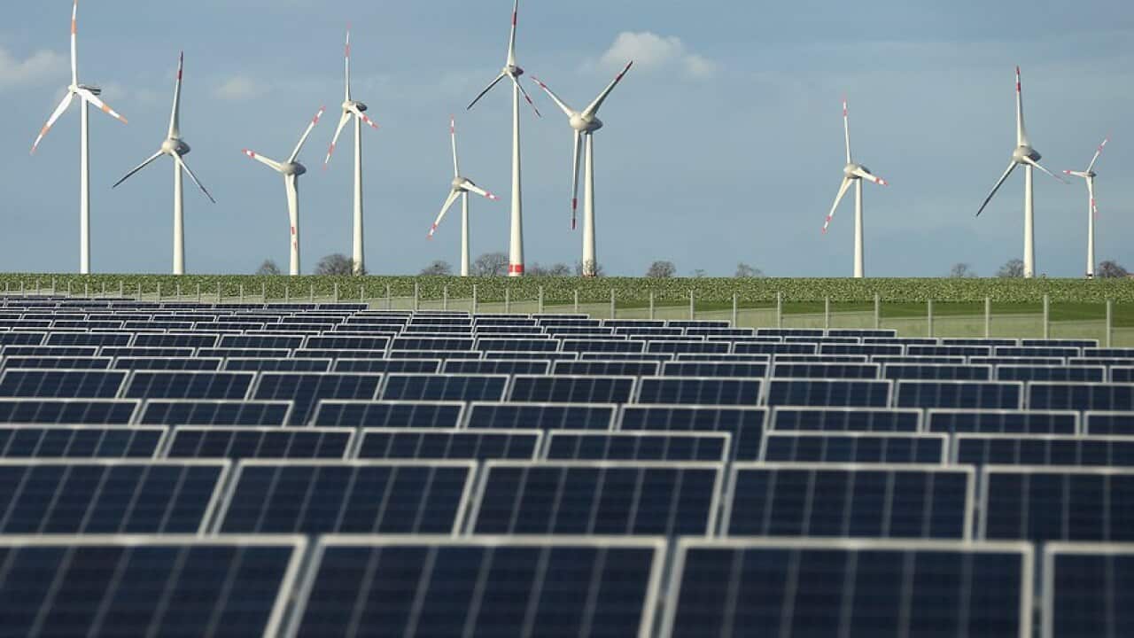 Wind turbines behind a solar power park in Germany