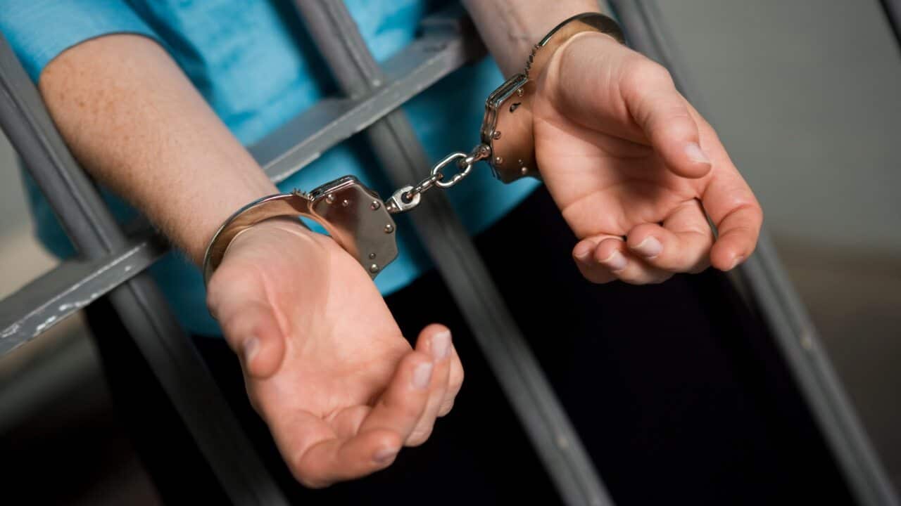Person handcuffed to prison bars