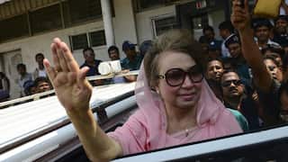 A woman in a saree waves at a crowd as she enters a car