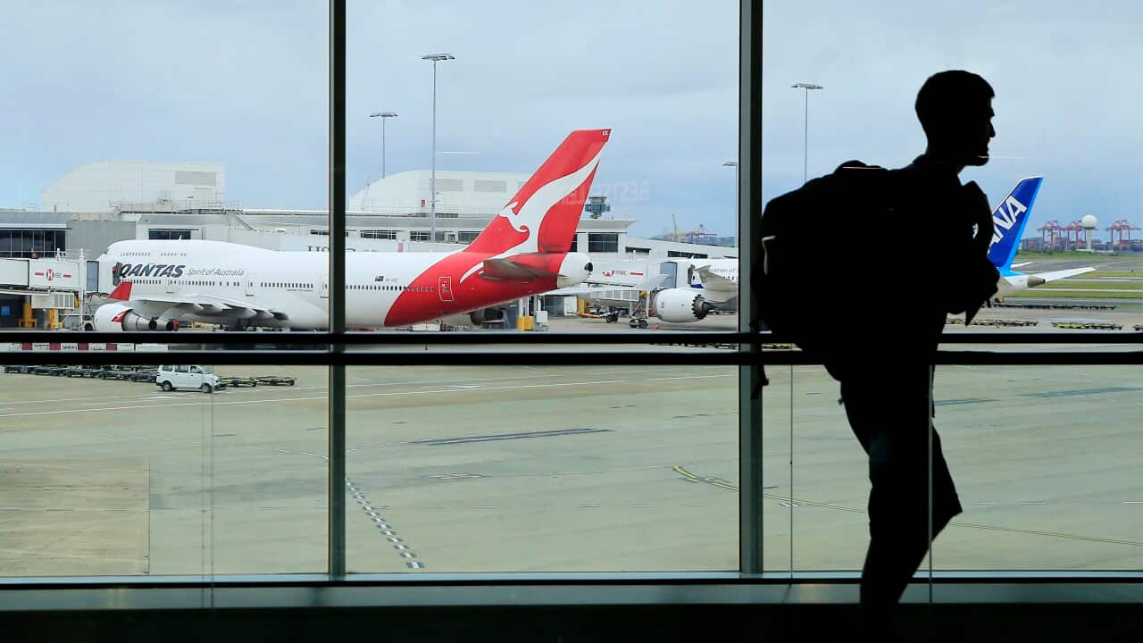 A man walking past a window at an airport. There are planes parked outside.