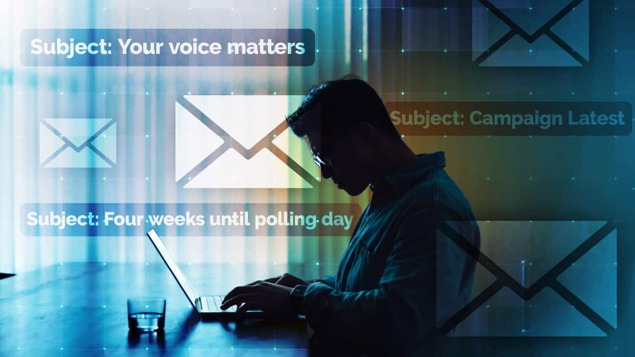 A man in dim light sitting at a laptop at a desk