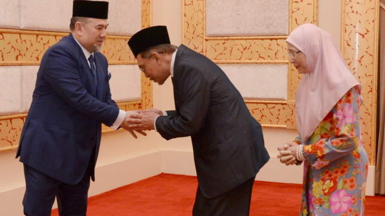 Malaysia's King Muhammad V, left, shakes hands with Anwar Ibrahim as Mr Anwar's wife, Wan Azizah, looks on at the Royal Palace in Kuala Lumpur (AAP)